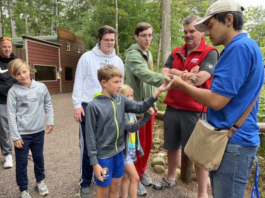 A family learning about snakes while on the wildlife education tour at the Northwoods Wildlife Center