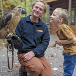 image of Bart (education director) holding a red tailed hawk and showing it to a kid
