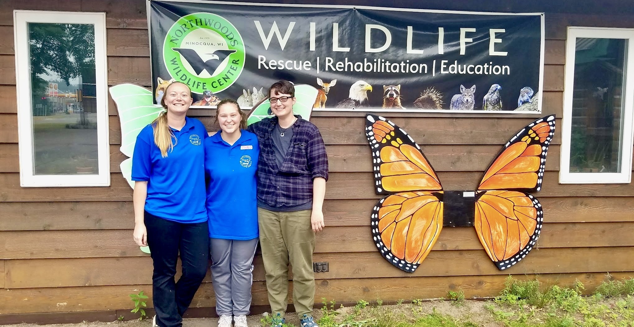 intern coordinator, Rafe, and 2 interns standing in front of Northwoods wildlife center sign