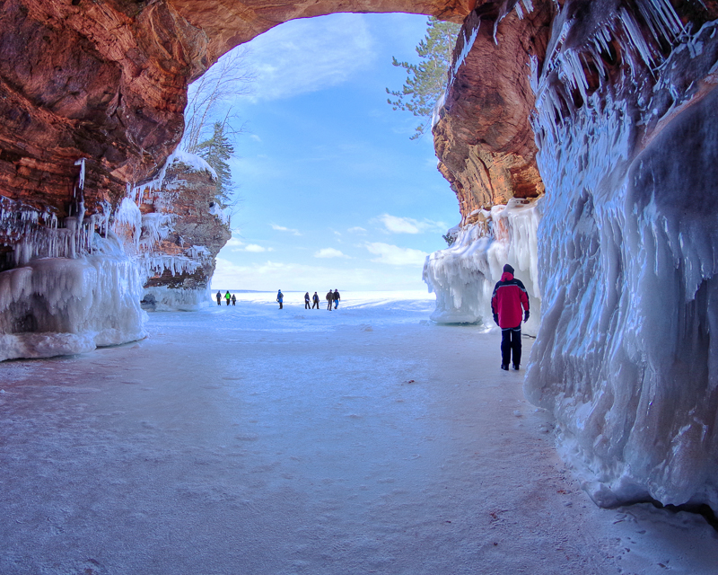 a view from inside a Lake Superior ice cave, looking out at people around the entrance