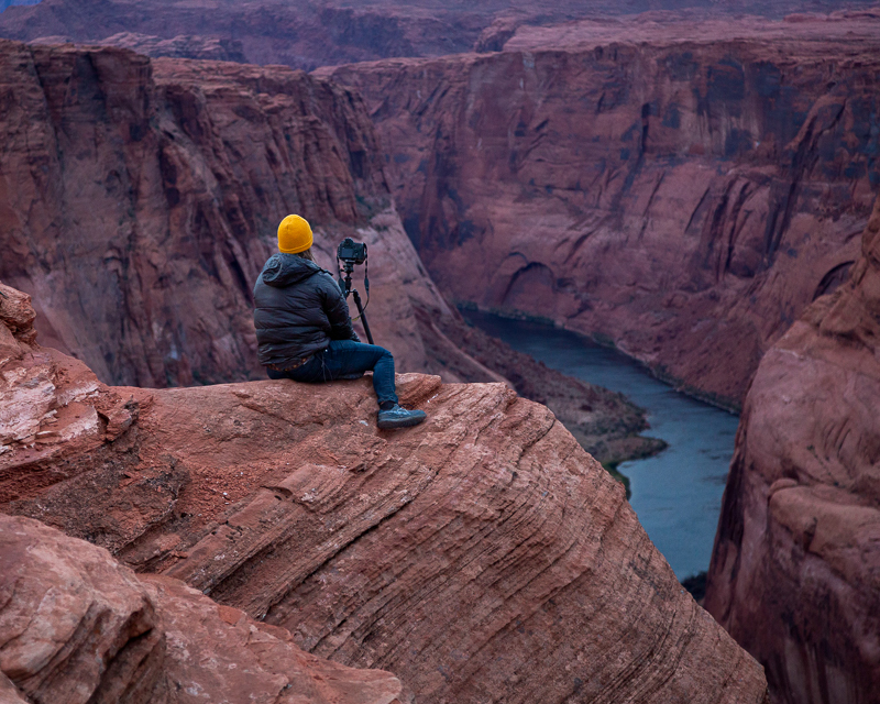 a photographer perched on a cliff looking over Horseshoe Canyon.