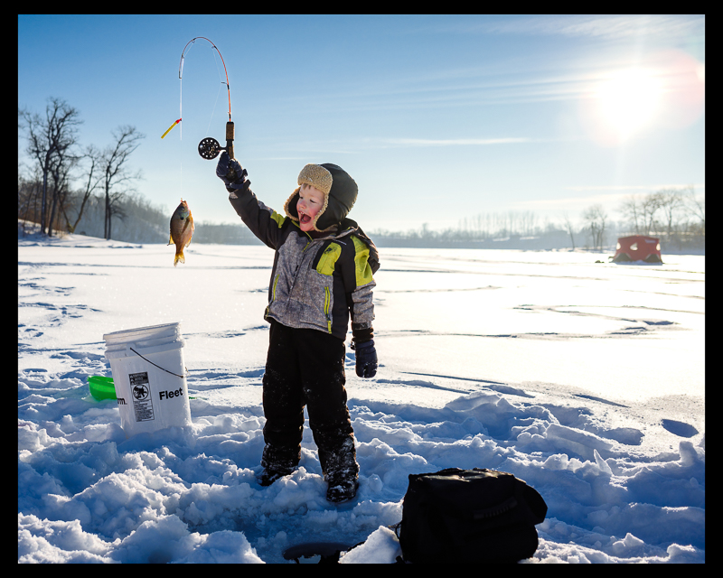 a young kid ice fishing and happy about his catch